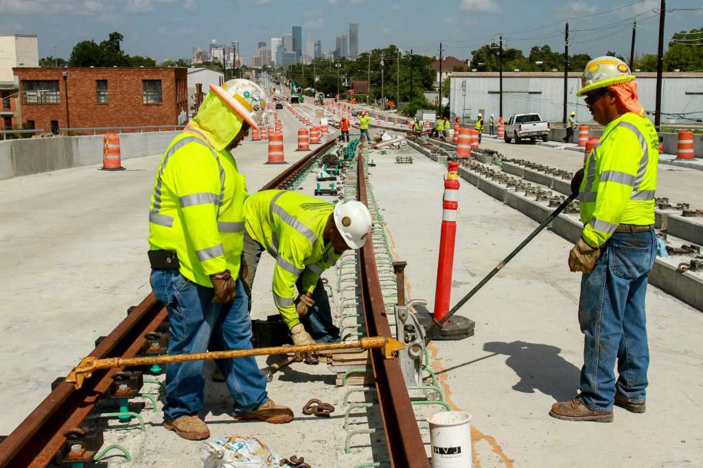 A railroad maintenance construction crew sets the gauge on a direct fixation rail before pouring concrete.